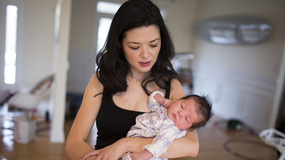 Ashlyn Nelson holds her four-week-old daughter, Suvi. Nelson is an economist and associate professor at Indiana University-Bloomington [James Brosher/Al Jazeera] 
