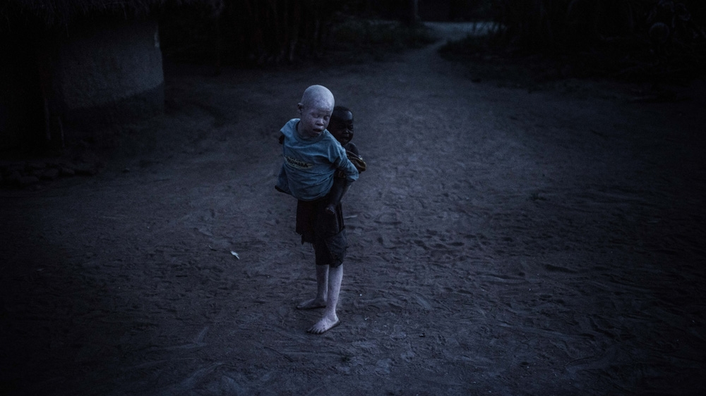 Semuju carries his youngest sister Marry, and tries to stop her from crying [Fredrik Lerneryd/Al Jazeera]