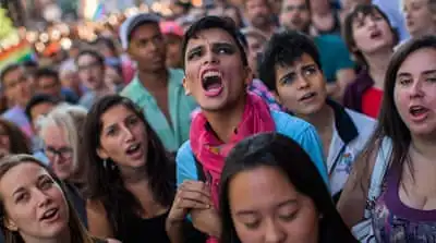 People shout slogans as they gather in front of a makeshift memorial to remember the victims of a mass shooting in Orlando [AP]