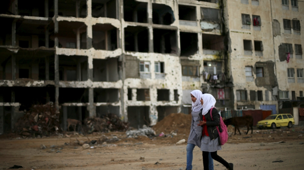 Palestinian schoolgirls walk past the remains of a residential building, destroyed during the 2014 war in the northern Gaza Strip on February 10, 2016 [Reuters]