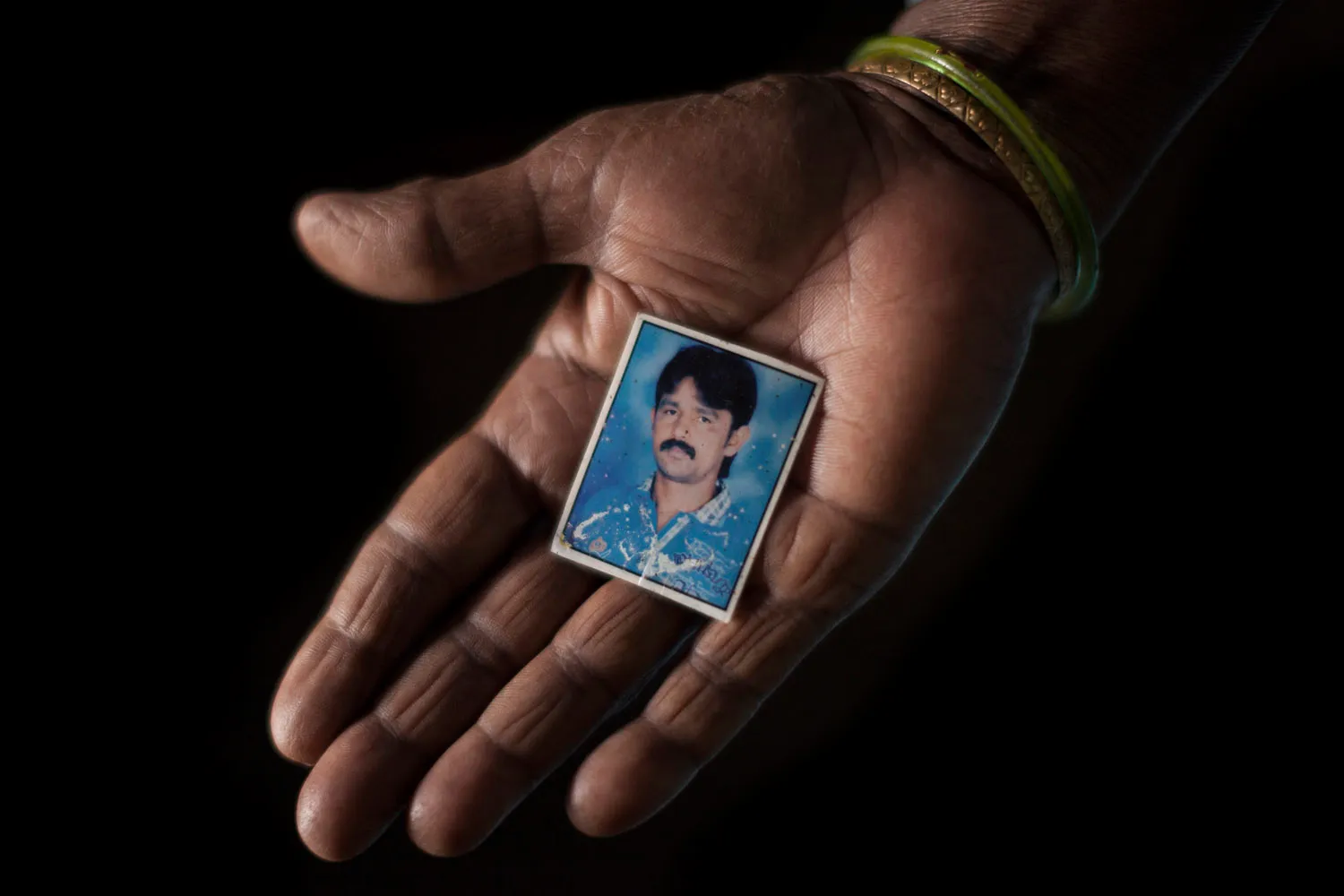 Savithriamma holds a photograph of her son Shivanna [Janos Chiala/Al Jazeera]