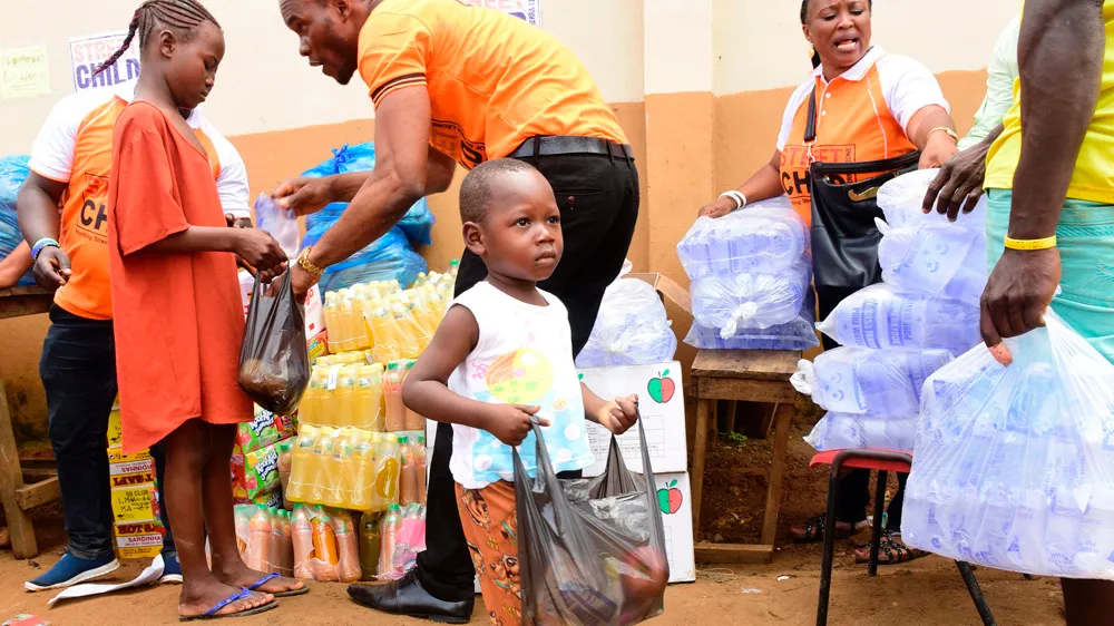 A child receives a bag of supplies from disaster relief volunteers on August 18, 2017, in Freetown, following heavy rains which resulted in more than 1000 deaths [SEYLLOU/AFP/Getty Images]