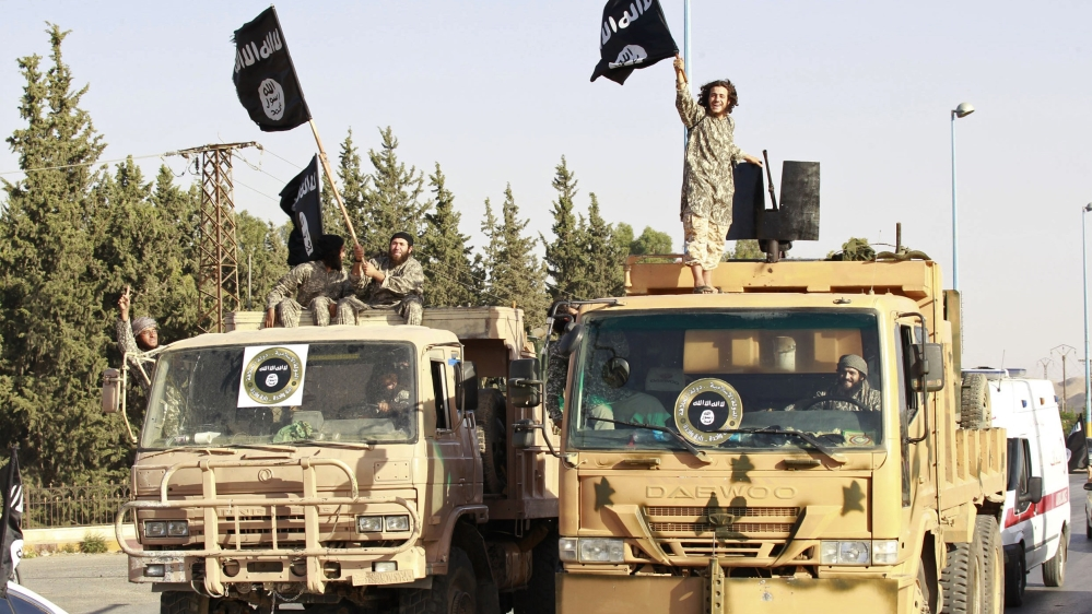 Militant Islamist fighters wave flags as they take part in a military parade along the streets of Raqqa
