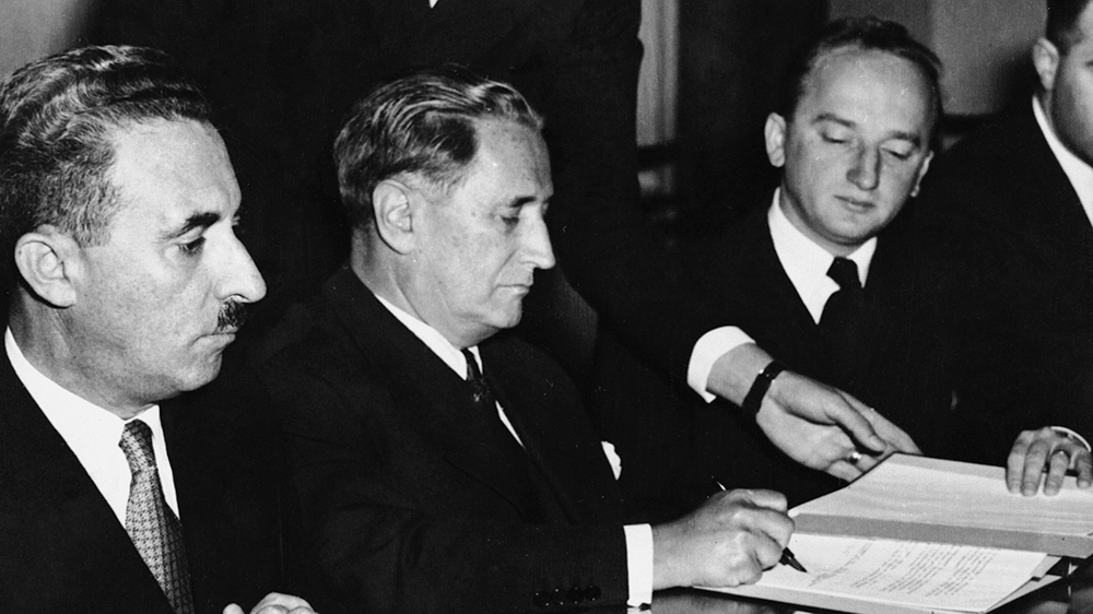 Nahum Goldmann, the president of the Jewish Claims Commission, centre, signs an agreement between Germany and Israel in Luxembourg on September 10, 1952. Benjamin Ferencz is to the right of the picture.