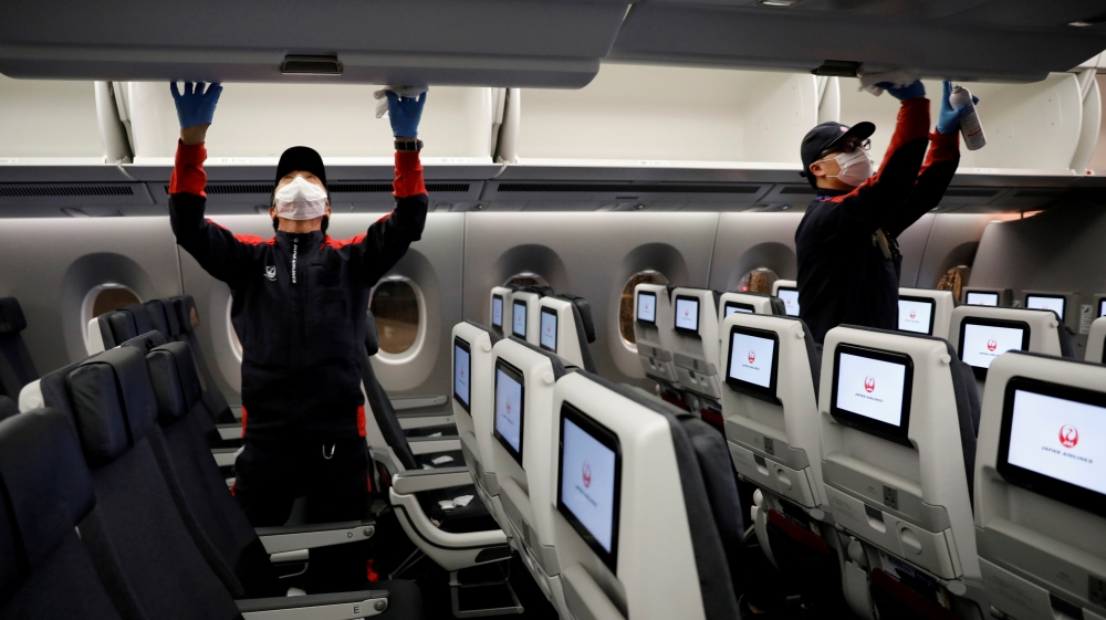 Japan Airlines’ staff members clean the cabin of a plane after a domestic flight at Haneda Airport, in Tokyo