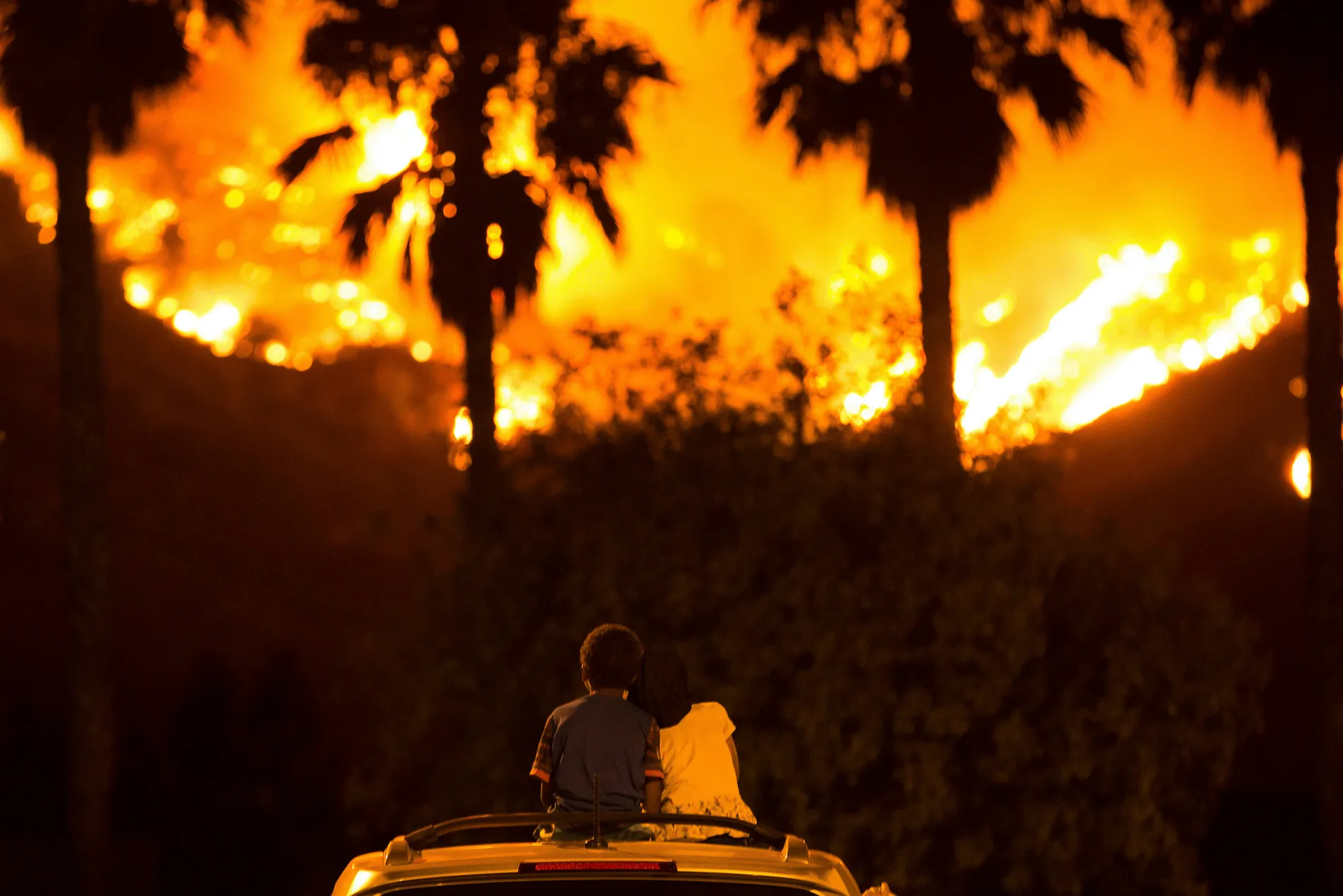 Six-year-old King Bass (left) sits and watches the Holy Fire burn from on top of his parents’ car as his five-year-old sister Princess rests her head on his shoulder on August 9, 2018 in Lake Elsinore, California