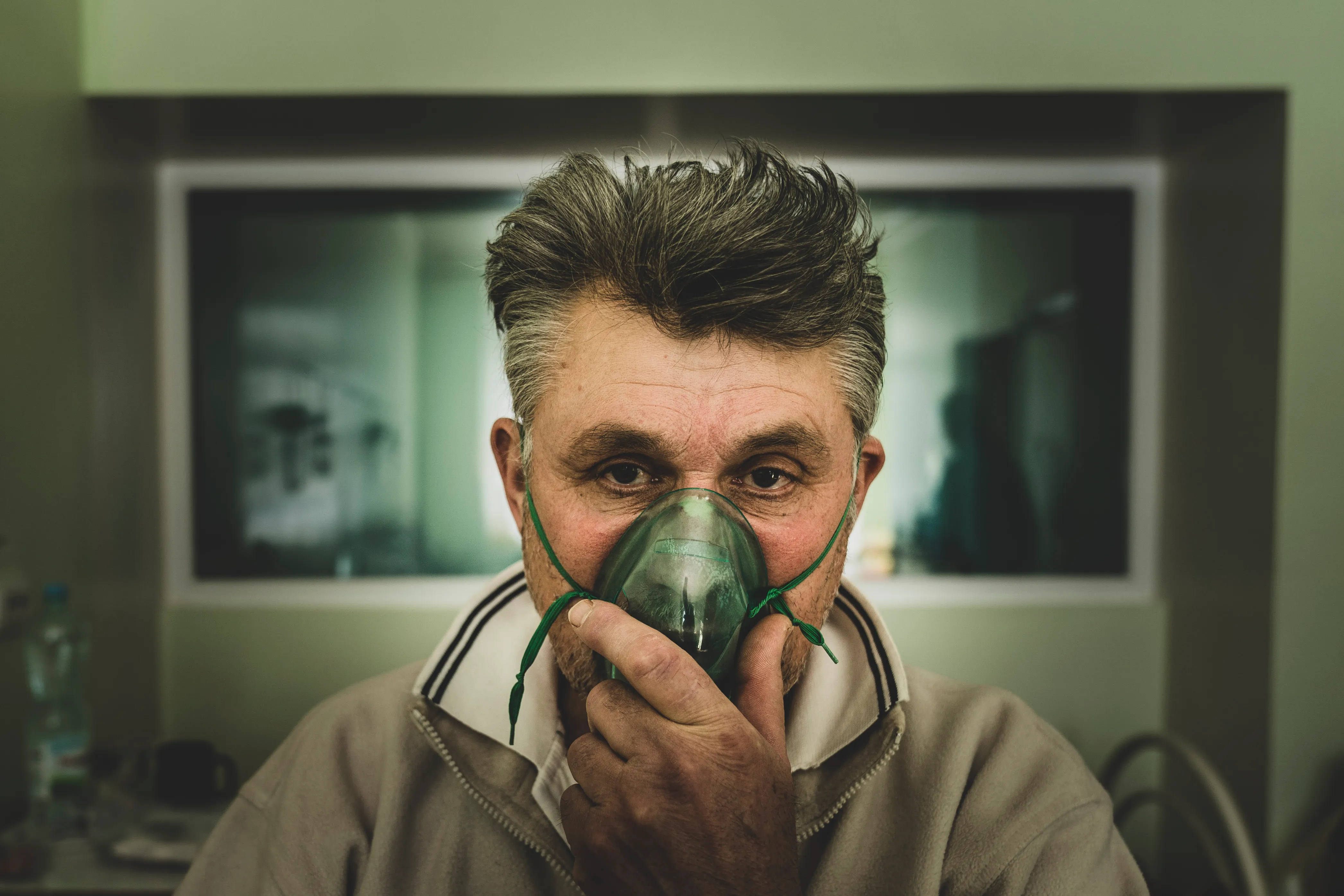 A coronavirus patient breathes in oxygen at a hospital's infectious disease ward in Sievierodonetsk in eastern Ukraine [Evgeniy Maloletka/Al Jazeera]