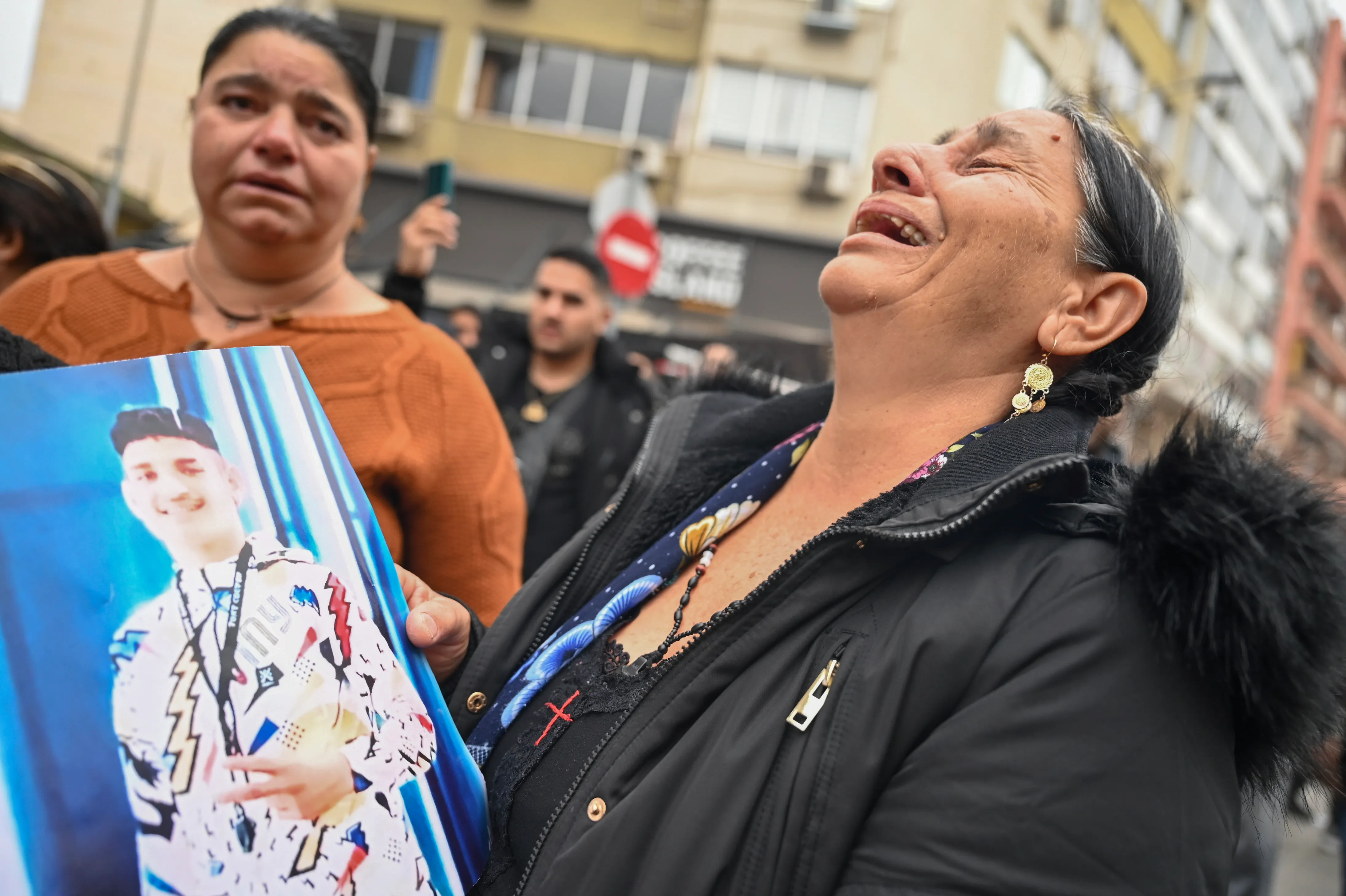 A woman reacts as she holds a photo of an injured 16-year-old teenager while relatives and other protesters from the Roma community protest outside the courthouse in Greece's second largest city of Thessaloniki
